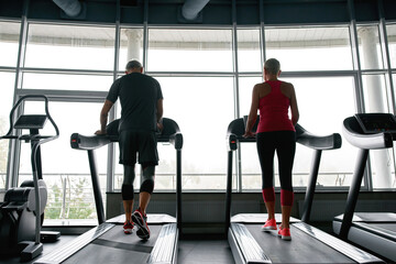 Active lifestyle. Middle-aged couple walking on treadmills