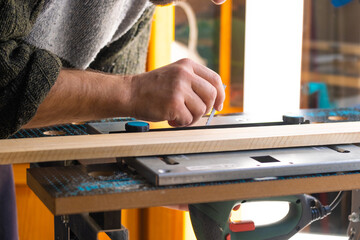 Confident wood worker expert. Young man working at factory. Skilled carpenter cutting a piece of wood in his woodwork workshop.