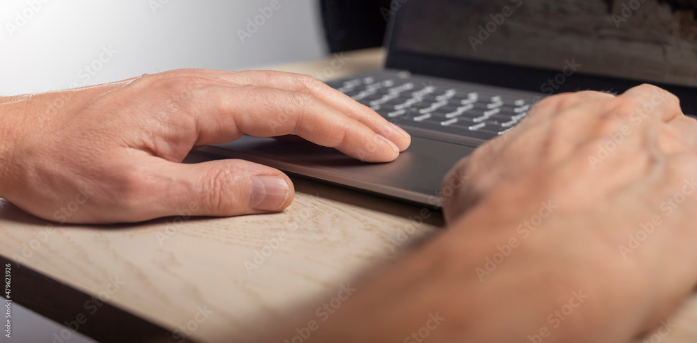 Poster hand on laptop touchpad, tapping and scrolling with fingers close up.
