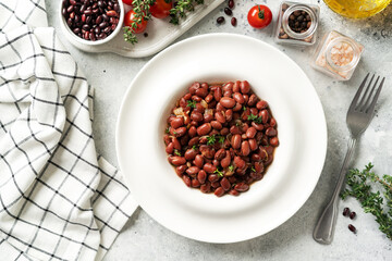 Stewed red beans with onion and thyme in tomato sauce in a white plate on the kitchen table top view