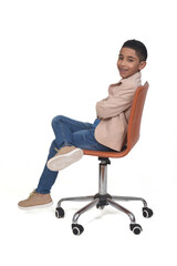 side view of a boy sitting a chair  looking at camera and legs and arms crossed on white background