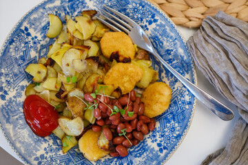 Homemade baked potatoes with nuggets and red beans in a blue vintage plate. Lunch