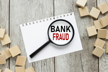 BANK FRAUD CONCEPT. text on magnifier glass on wood background