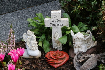 Grabgestaltung auf einem christlichen Friedhof in &Ouml;sterreich mit Engeln, Kreuz und Trauerspruch "in stillem Gedenken"