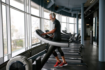 Handsome man running on treadmill at gym