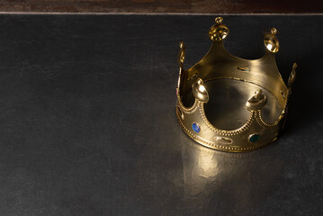 Golden crown on the old black table baackground with copy space.