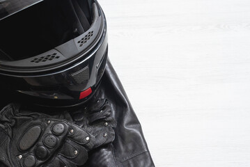 Motorcycle helmet, protective gloves and leather jacket on the white table background with copy...