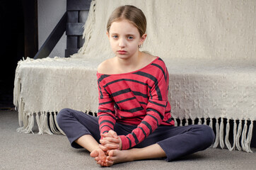 Girl's bare feet. Foot heel. Sad little girl sitting on the floor. European