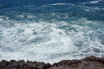 Waves crash on rocks near the Incekum Natural Park in Turkey on the shores of the Mediterranean Sea. Sky blue water. Selective focus. Close-up