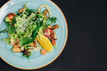 The professional chef made a new dish in the blue plate and placed it on the black table.