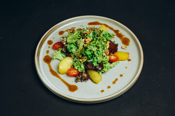 There is a new salad that includes potatoes on the black table of the restaurant.