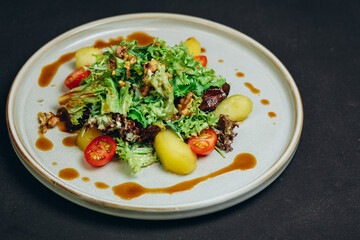 We can see a new dish or salad in the white plate on the black table of the cafe.