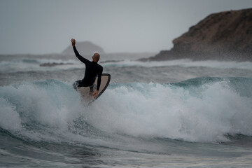 Senior man with black wetsuit, surfs a wave in Gran Canaria