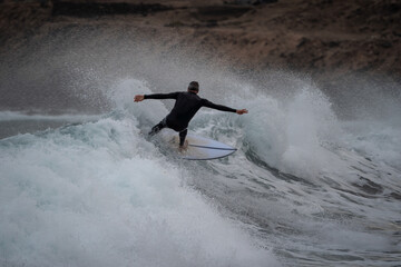 Senior man with black wetsuit, surfs a wave in Gran Canaria - obrazy, fototapety, plakaty