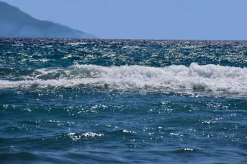 Seascape at noon. Mountains over sea. Water surface texture and waves close-up. Wondeful weather, climate change.