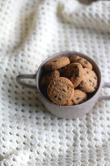 Bowl of chocolate chip cookies and soft knitted blanket. Hygge at home. Selective focus.