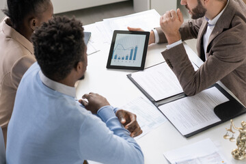 Young African couple listening to male lawyer or economist with tablet making presentation of online data