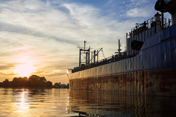 Fragment of the ship near the pier against of a colorful sunset over Danube river