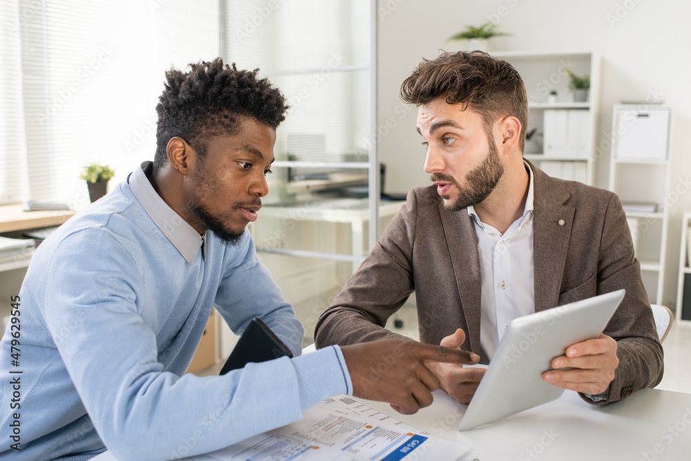 Poster one of two confident businessmen explaining online data to colleague during discussion of financial 