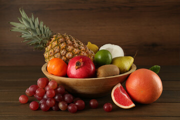 Fresh ripe fruits and bowl on wooden table