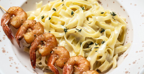Close up Seafood tagliatelle pasta with grilled shrimps, bechamel sauce and thyme, fettuccine pasta. Italian food. Healthy diet seafood concept. Top view