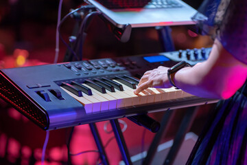 Close shooting of a keyboardist musician at work at a concert. Keyboardist play keyboard on stage