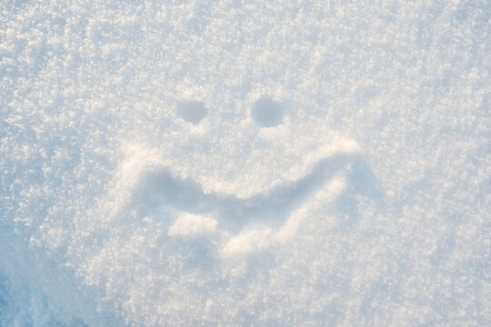 Cute smiley face drawn on the snow on a sunny winter day. Top view.
