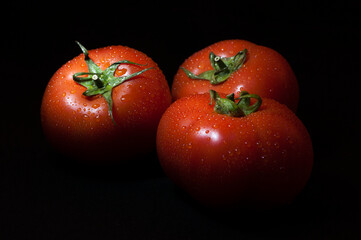 Fresh tomatoes with drops isolated on black background.