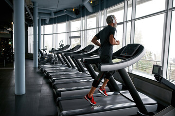 Fototapeta na wymiar Mature man while cardio workout in gym