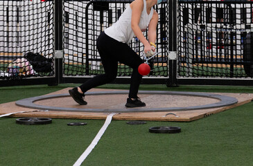 Girl throwing the weight indoors at a track meet