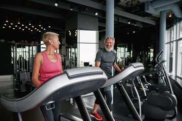 Aged couple exercising side by side in gym