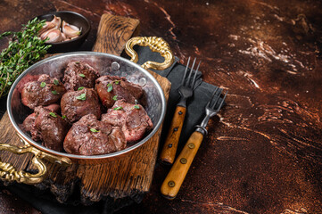 Roasted beef kidney, offal meat in skillet with herbs. Dark background. Top view. Copy space