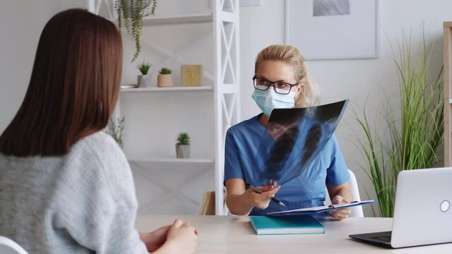 Medical consultation. Female doctor. Labs result. Confident woman showing x-ray photo to female patient in light room interior.