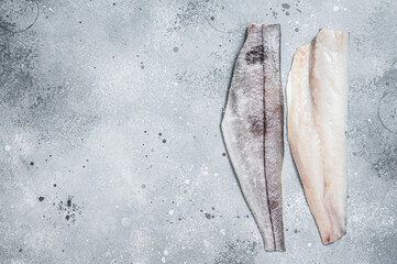 Two raw haddock fish fillets on kitchen table. Gray background. Top view. Copy space