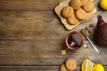 Flat lay composition with tea bag in glass cup of hot water on wooden table, space for text