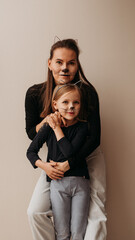 Family fun, face-painting cat mothers and daughter at wall