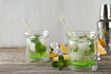 Delicious cocktails with mint and ice balls on wooden table