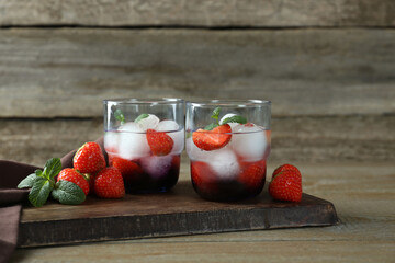 Delicious cocktails with strawberries, mint and ice balls on wooden table