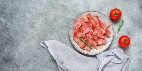 Slices of prosciutto crudo parma or jamon serrano on gray grunge background. Top view, flat lay. Banner - obrazy, fototapety, plakaty