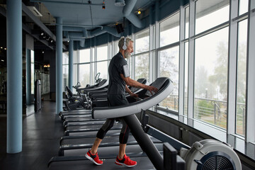 Fototapeta na wymiar Aged sportsman exercising on treadmill in gym