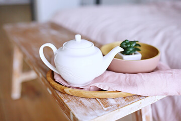 Fototapeta na wymiar Breakfast in bed. White porcelain teapot on wooden bench 