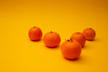 Bright orange tangerines lie on a yellow background