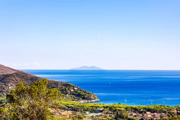 Fotobehang View over the village of Marina del Campo and the blue sea to the island of Monte Christo on the island of Elba in Italy under a bright blue sky in summer © were