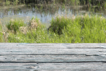 Old wooden table front view with copy space on the green meadow background.