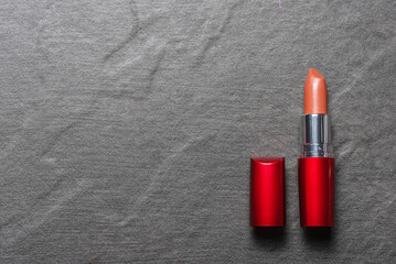 Red lipstick on the dark black flat lay background with copy space.