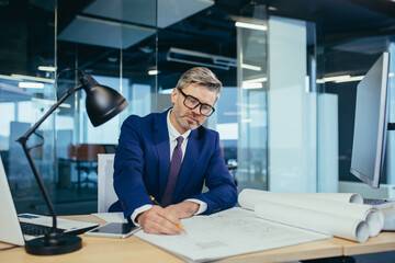 Successful and experienced male designer working in the office on the project, making adjustments...