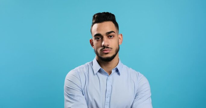 Portrait Of Serious Young Businessman Over Blue Background