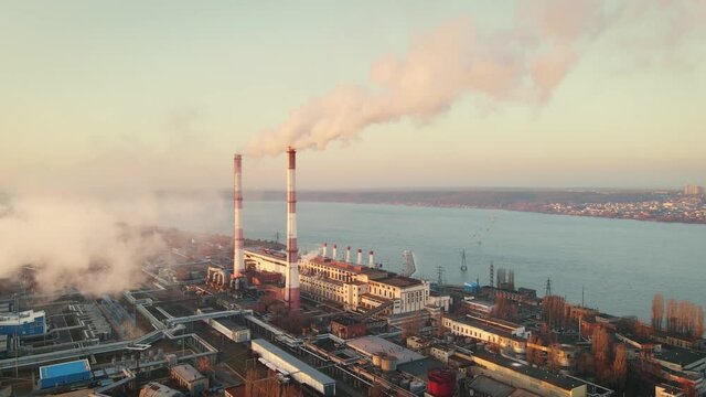 Aerial view of high smoke stack with smoke emission. Plant pipes pollute atmosphere. Industrial factory pollution, smokestack exhaust gases. Industry zone, thick smoke plumes. Climate change, ecology