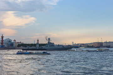 Russian military ship on the Neva in the center of the city surrounded by pleasure boats with tourists against the background of a blue sky