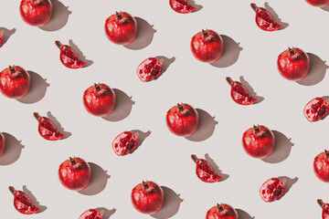 Creative pattern made of fresh pomegranates on pastel grey background with sunlit. Minimal style. Top view. Flat lay .